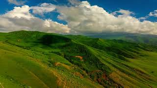 White clouds flying over green foothills at sunny summer day in Kyrgyzstan drawn point of view time [upl. by Vidovik]