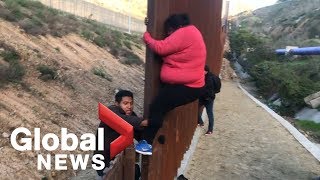 Migrant families continue to spill over Tijuana border fence head to US [upl. by Manup]